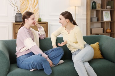 Photo of Friends laughing on sofa indoors. Positive emotion