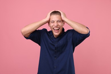 Photo of Handsome man laughing on pink background. Positive emotion