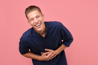 Photo of Handsome man laughing on pink background. Positive emotion