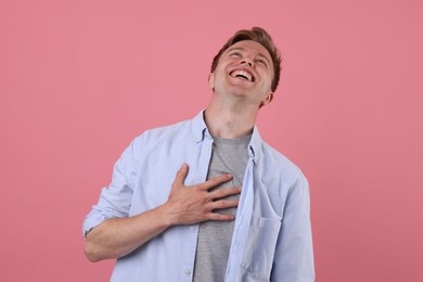 Photo of Handsome man laughing on pink background. Positive emotion