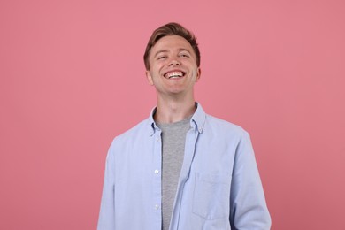 Photo of Handsome man laughing on pink background. Positive emotion