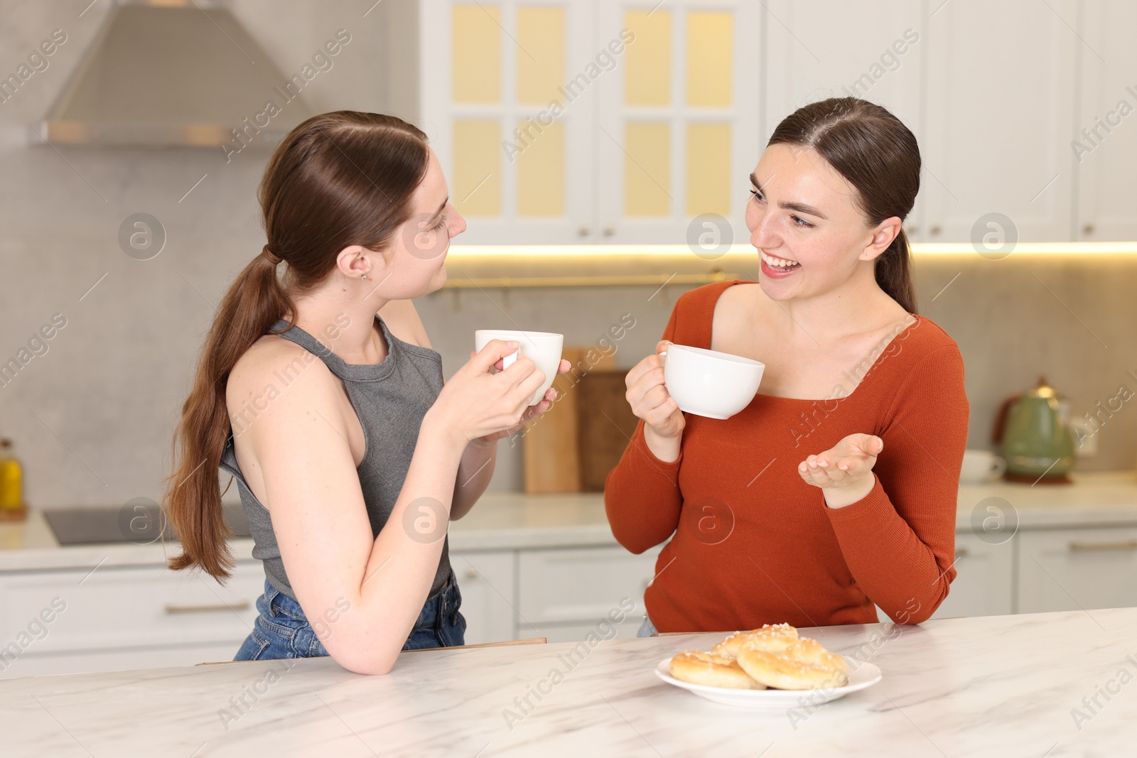 Women with coffee laughing in kitchen. Positive emotion Photo of Women with coffee laughing in kitchen. Positive emotion