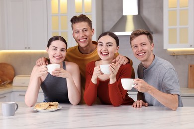 Photo of Friends with coffee laughing in kitchen. Positive emotion