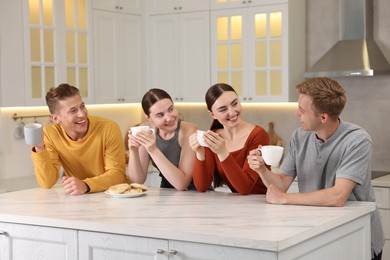 Photo of Friends with coffee laughing in kitchen. Positive emotion
