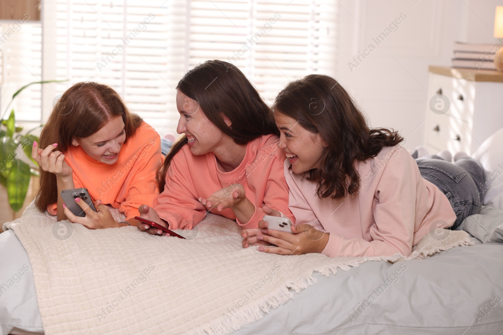 Photo of Friends with smartphones on bed at home