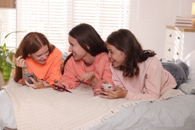 Photo of Friends with smartphones on bed at home