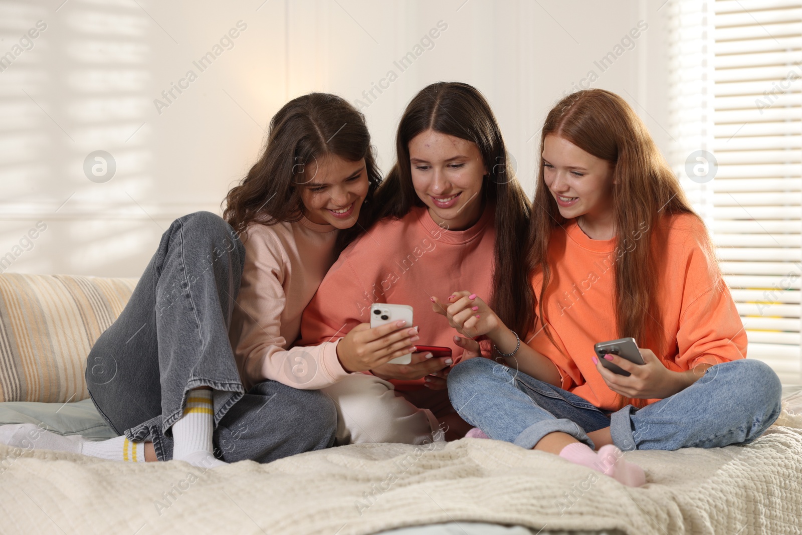 Photo of Friends with smartphones on bed at home