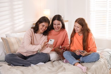 Photo of Friends with smartphones on bed at home