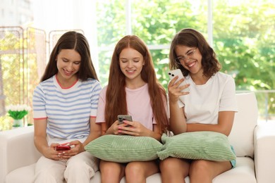 Photo of Friends with smartphones on sofa at home