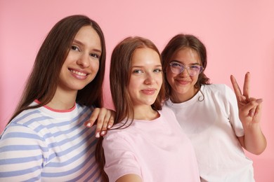 Photo of Happy friends taking selfie on pink background
