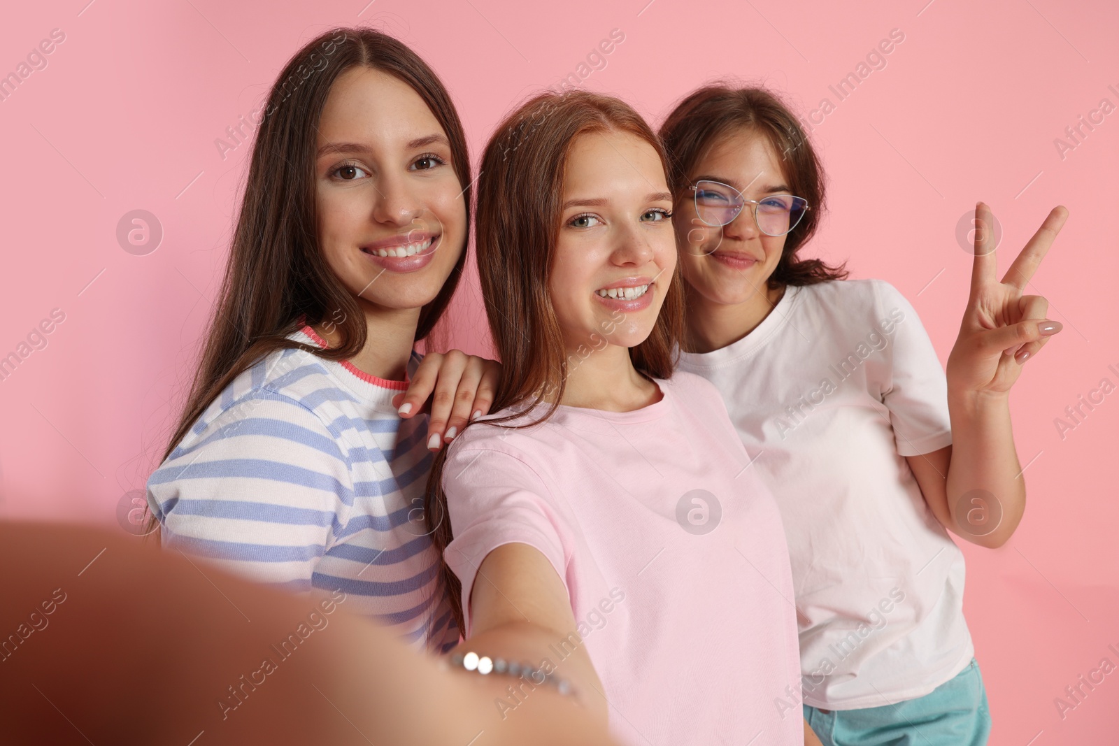 Happy friends taking selfie on pink background Photo of Happy friends taking selfie on pink background