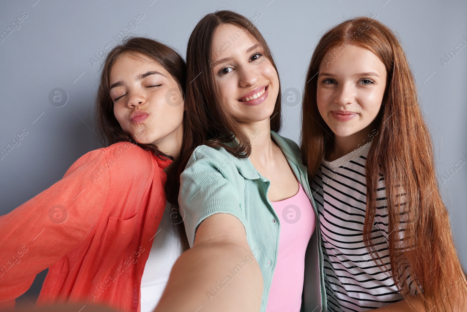 Photo of Happy friends taking selfie on grey background