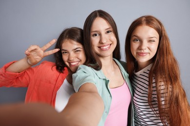 Photo of Happy friends taking selfie on grey background