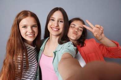 Photo of Happy friends taking selfie on grey background