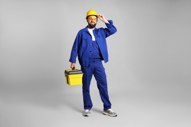 Photo of Professional repairman with tool box on grey background