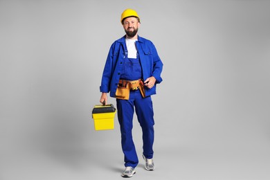 Photo of Professional repairman with tool box on grey background