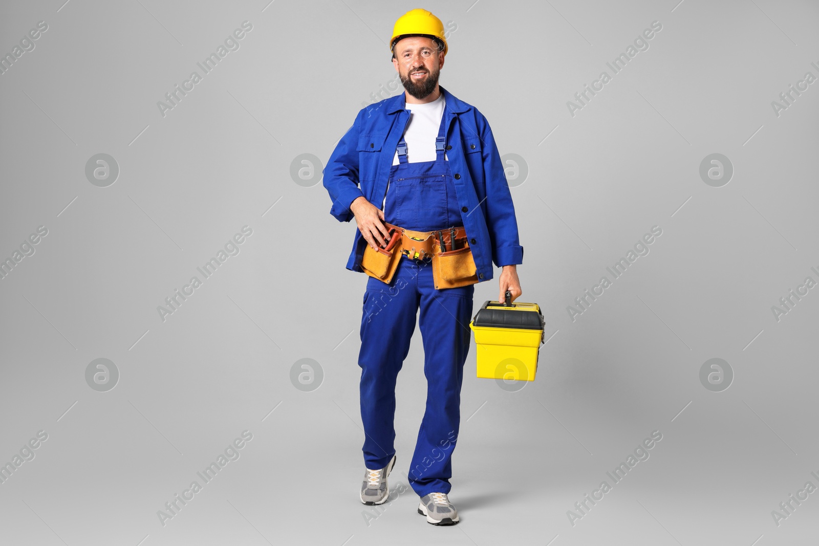 Professional repairman with tool box on grey background Photo of Professional repairman with tool box on grey background