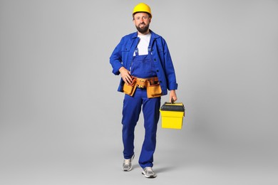 Photo of Professional repairman with tool box on grey background