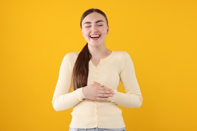 Photo of Beautiful woman laughing on yellow background. Positive emotion