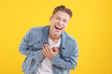 Photo of Handsome man laughing on yellow background. Positive emotion