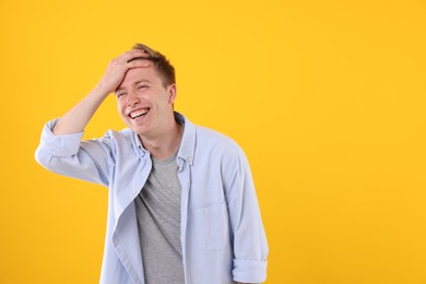 Photo of Handsome man laughing on yellow background. Space for text