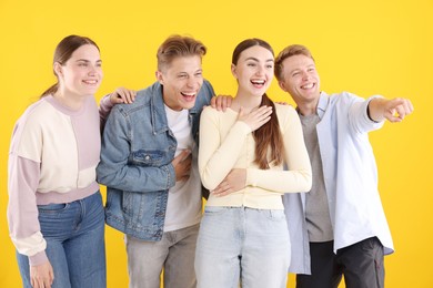 Photo of Friends laughing and looking at something on yellow background. Positive emotion