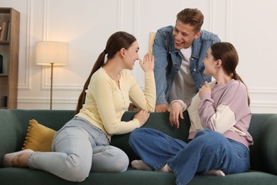 Photo of Friends laughing on sofa indoors. Positive emotion
