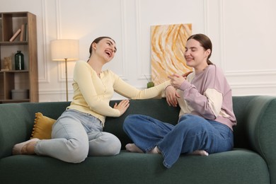 Photo of Friends laughing on sofa indoors. Positive emotion