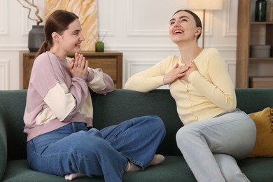 Photo of Friends laughing on sofa indoors. Positive emotion