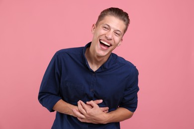 Photo of Handsome man laughing on pink background. Positive emotion
