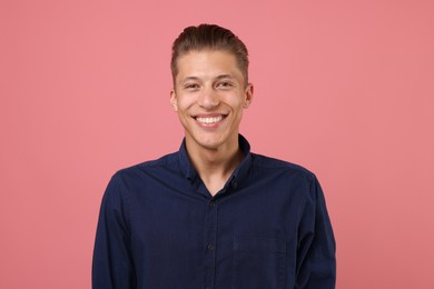 Photo of Handsome man laughing on pink background. Positive emotion