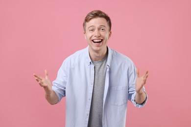 Photo of Handsome man laughing on pink background. Positive emotion
