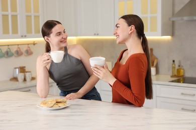 Photo of Women with coffee laughing in kitchen. Positive emotion