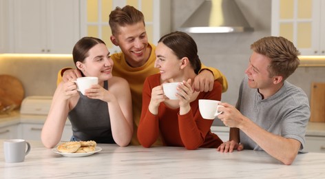 Photo of Friends with coffee laughing in kitchen. Positive emotion