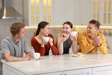 Photo of Friends with coffee laughing in kitchen. Positive emotion