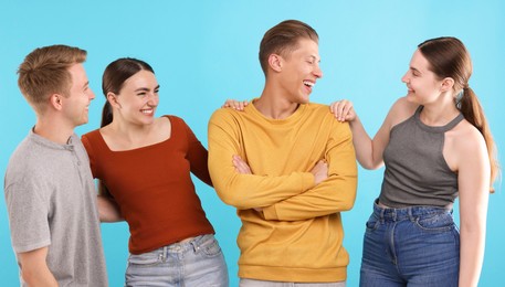 Photo of Friends laughing on light blue background. Positive emotion