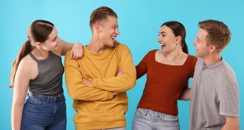 Photo of Friends laughing on light blue background. Positive emotion