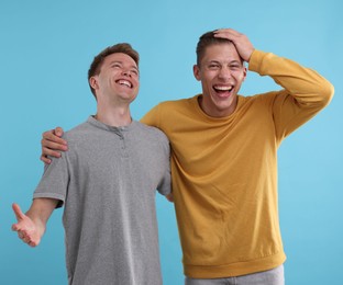 Photo of Handsome men laughing on light blue background. Positive emotion