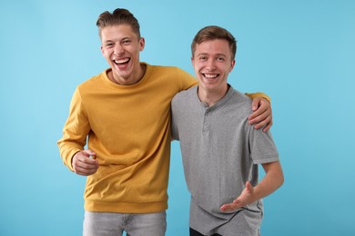 Photo of Handsome men laughing on light blue background. Positive emotion