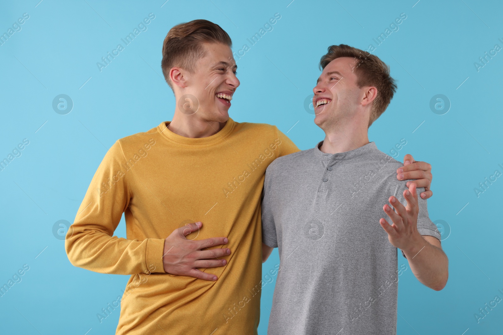 Handsome men laughing on light blue background. Positive emotion Photo of Handsome men laughing on light blue background. Positive emotion