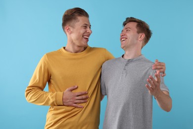 Photo of Handsome men laughing on light blue background. Positive emotion