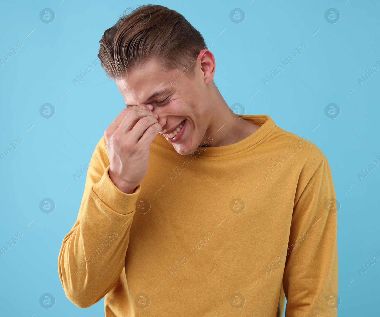 Handsome man laughing on light blue background. Positive emotion Photo of Handsome man laughing on light blue background. Positive emotion