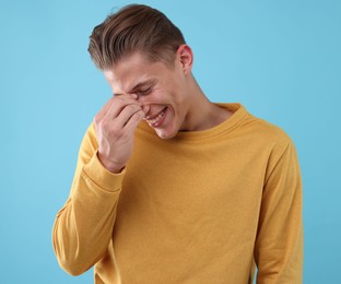 Photo of Handsome man laughing on light blue background. Positive emotion