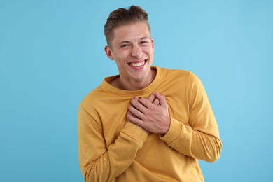 Photo of Handsome man laughing on light blue background. Positive emotion