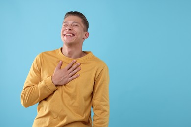 Photo of Handsome man laughing on light blue background. Space for text