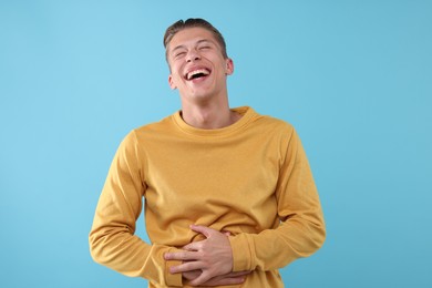 Photo of Handsome man laughing on light blue background. Positive emotion