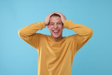 Photo of Handsome man laughing on light blue background. Positive emotion