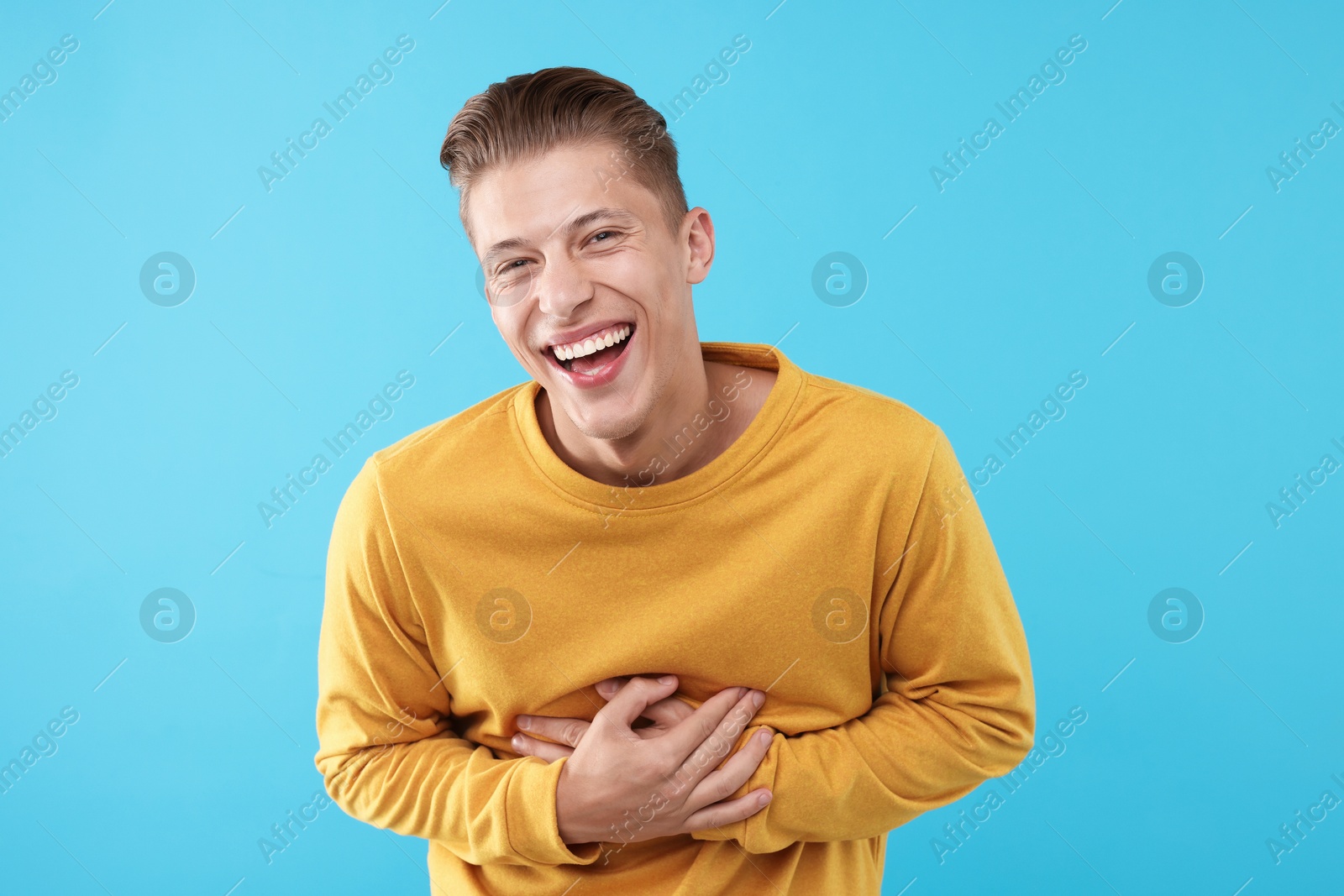 Handsome man laughing on light blue background. Positive emotion Photo of Handsome man laughing on light blue background. Positive emotion