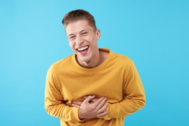 Photo of Handsome man laughing on light blue background. Positive emotion