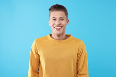 Photo of Handsome man laughing on light blue background. Positive emotion